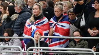 Warga Inggris menyaksikan iring-iringan yang membawa peti mati Ratu elizabeth II saat tiba di Kastil Windsor, Inggris, Senin (19/9/2022). [Paul ELLIS / POOL / AFP]
