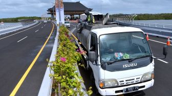 Pekerja menyiram tanaman di median pembatas Jalan Tol Bali Mandara, Bali, Rabu (21/9/2022). [ANTARA FOTO/Fikri Yusuf/nym].