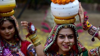 Peserta dari kelompok seni yang mengenakan pakaian tradisional berpose saat latihan tari Garba menjelang festival Navratri di Ahmedabad, India, Selasa (20/9/2022). [SAM PANTHAKY / AFP]