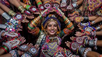 Peserta dari kelompok seni mengenakan pakaian tradisional berlatih tari Garba menjelang festival Navratri di Ahmedabad, India, Selasa (20/9/2022). [SAM PANTHAKY / AFP]
