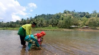 Dua bocah mengambil air sungai pada tradisi Mandi Safar di Desa Buata, Kabupaten Gorontalo Utara, Gorontalo, Rabu (21/9/2022). [ANTARA FOTO/Adiwinata Solihin/nz]