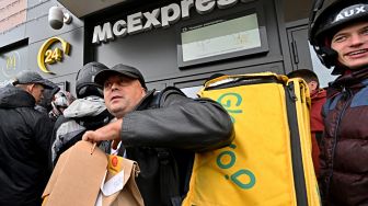Kurir pengiriman makanan Glovo mengambil pesanan di sebuah restoran McDonald di Kyiv, Ukraina, Selasa (20/9/2022). [Sergei SUPINSKY / AFP]