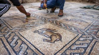 Petani Palestina Salman al-Nabahin dan Putranya saat membersihkan mozaik Bizantium yang ditemukan di tanahnya di Bureij, Gaza, Palestina, Minggu (18/9/2022). [AFP PHOTO/MOHAMMED ABED]
