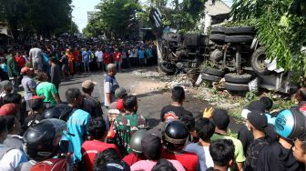 Warga menyaksikan proses evakuasi truk tangki pengangkut BBM berkapasitas 16 ribu liter yang mengalami kecelakaan di Simpang Tiga Sukowidi, Banyuwangi, Jawa Timur, Minggu (25/09/2022).  ANTARA FOTO/Budi Candra Setya