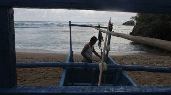 Seorang nelayan membersihkan perahu miliknya di pantai Kondangmerak, Malang, Jawa Timur, Sabtu (24/9/2022).  ANTARA FOTO/Ari Bowo Sucipto