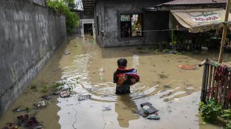 Seorang warga membawa barang-barang saat mengungsi dari rumahnya yang terendam banjir setelah terjangan Topan Noru di San Ildefonso, Provinsi Bulacan, Filipina, Senin (26/9/2022). [Ted ALJIBE / AFP]