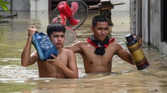 Warga membawa barang-barang saat mengungsi dari rumahnya yang terendam banjir setelah terjangan Topan Noru di San Ildefonso, Provinsi Bulacan, Filipina, Senin (26/9/2022). [Ted ALJIBE / AFP]
