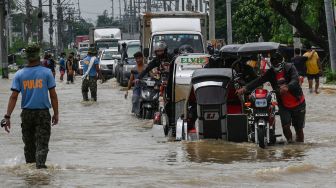 Warga dan pengendara motor berusahan melewati banjir di sepanjang jalan raya setelah terjangan Topan Noru di San Ildefonso, Provinsi Bulacan, Filipina, Senin (26/9/2022). [Ted ALJIBE / AFP]