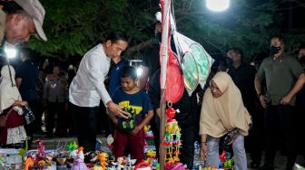 Presiden Joko Widodo membelikan mainan untuk seorang anak saat mengunjungi pasar malam di kawasan Pantai Kamali, Kota Baubau, Sulawesi Tenggara, Senin (26/9/2022).[ANTARA FOTO/Frans/JJ/rwa].