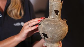 Petugas dari Israel Antiquities Authority (IAA) memegang salah satu bejana yang diyakini berisi opium dari abad ke-14 SM yang ditemukan di situs pemakaman Tel Yehud dan sekarang dipajang di kantor IAA di Yerusalem, Israel, Selasa (20/9/2022). [AHMAD GHARABLI/AFP]