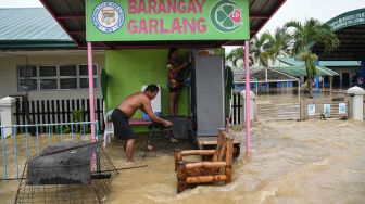 Warga menempatkan barang-barang mereka di tempat penyimpanan dari rumahnya yang terendam banjir setelah terjangan Topan Noru di San Ildefonso, Provinsi Bulacan, Filipina, Senin (26/9/2022). [Ted ALJIBE / AFP]
