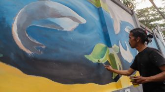 Para seniman menyelesaikan pembuatan mural tematik  di salah satu tembok di Taman Margasatwa Ragunan, Jakarta Selatan. Rabu (28/9/2022). [Suara.com/Alfian Winanto]