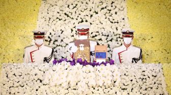 Seorang prajurit Jepang (tengah) memegang guci berisi abu mantan perdana menteri Jepang Shinzo Abe selama pemakaman kenegaraannya di Nippon Budokan, Tokyo, Jepang, Selasa (27/9/2022). [Takashi Aoyama / POOL / AFP]
