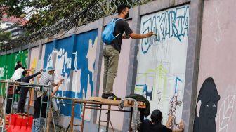 Para seniman menyelesaikan pembuatan mural tematik  di salah satu tembok di Taman Margasatwa Ragunan, Jakarta Selatan. Rabu (28/9/2022). [Suara.com/Alfian Winanto]