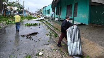 Orang-orang membersihkan jalanan usai diterjang Badai Ian di Consolacion del Sur, Kuba, Selasa (27/9/2022). [ADALBERTO ROQUE / AFP]