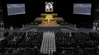 Potret mantan perdana menteri Jepang Shinzo Abe tergantung di atas panggung saat pemakaman kenegaraannya di Nippon Budokan, Tokyo, Jepang, Selasa (27/9/2022). [Takashi Aoyama / POOL / AFP]