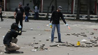 Anggota tim identifikasi gabungan dari Polres Malang dan Polda Jatim melakukan Olah Tempat Kejadian Perkara (TKP) kerusuhan di depan Stadion Kanjuruhan, Malang, Jawa Timur, Minggu (2/10/2022). [ANTARA FOTO/Ari Bowo Sucipto/foc]