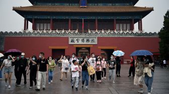 Orang-orang berjalan dari pintu keluar Kota Terlarang saat hari pertama libur Hari Nasional China di Beijing, Sabtu (1/20/2022). [Noel SELIS / AFP]
