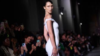 Model Bella Hadid tampil di catwalk dengan slip dress yang disemprot dengan kain Fabrican Spray-on selama peragaan busana Coperni Spring-Summer 2023 yang merupakan bagian dari Paris Fashion Week di Paris, Prancis, Jumat (30/9/2022). [JULIEN DE ROSA / AFP]
