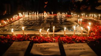 Ultras Garuda bersama Gabungan suporter klub di Indonesia melakukan aksi 1000 lilin dan tabur bunga di depan Kompleks Gelora Bung Karno, Jakarta Pusat, Minggu (2/10/2022). [Suara.com/Alfian Winanto]