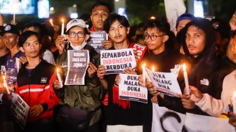 Ultras Garuda bersama Gabungan suporter klub di Indonesia melakukan aksi 1000 lilin dan tabur bunga di depan Kompleks Gelora Bung Karno, Jakarta Pusat, Minggu (2/10/2022). [Suara.com/Alfian Winanto]