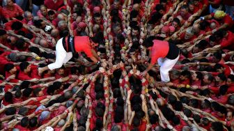 Anggota tim menara manusia "Jove de Valls" berusaha membentuk "castell" (menara manusia) selama kompetisi 'castells' edisi ke-28 di arena Tarraco di Tarragona, Catalunya, Spanyol, Minggu (2/10/2022). [Josep LAGO / AFP]
