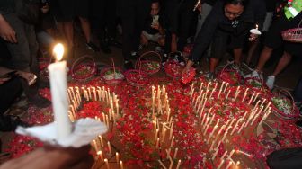 Suporter Persebaya memegang lilin saat mengikuti doa bersama di Tugu Pahlawan, Surabaya, Jawa Timur, Senin (3/10/2022).  ANTARA FOTO/Didik Suhartono