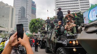 Warga berswafoto dengan kendaraan alutsista milik TNI yang dipamerkan di Bundaran HI, Jakarta Selatan, Rabu (5/10/2022). [Suara.com/Alfian Winanto]