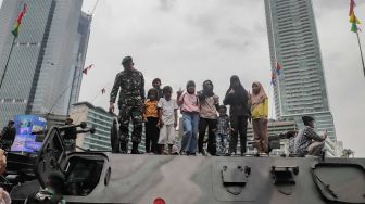 Warga berswafoto dengan kendaraan alutsista milik TNI yang dipamerkan di Bundaran HI, Jakarta Selatan, Rabu (5/10/2022). [Suara.com/Alfian Winanto]