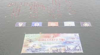 Sejumlah prajurit TNI dan Polri serta sipil mengapung di air tanpa berpindah tempat (Water Trappen) membentuk tulisan 'TNI' di Perairan Pantai Marina, Jakarta, Rabu (5/10/2022). [ANTARA FOTO/M Risyal Hidayat/nz]