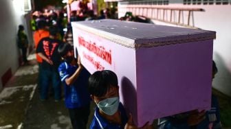 Personel penyelamat membawa peti mati korban korban penembakan massal di kamar mayat rumah sakit di Udon Thani, Thailand, Kamis (6/10/2022). [Manan VATSYAYANA / AFP]
