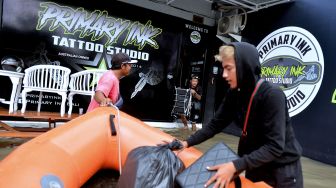 Warga memindahkan peralatan dari studio tato yang terendam banjir di kawasan Legian, Badung, Bali, Sabtu (8/10/2022). ANTARA FOTO/Fikri Yusuf

