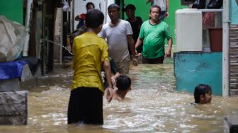 Warga beraktivitas saat banjir yang melanda kawasan Kebon Pala, Jakarta Timur, Senin (10/10/2022). [Suara.com/Alfian Winanto]
