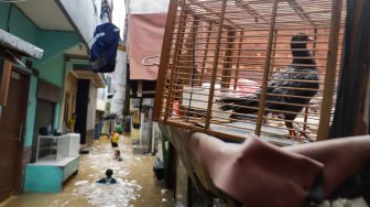 Warga beraktivitas saat banjir yang melanda kawasan Kebon Pala, Jakarta Timur, Senin (10/10/2022). [Suara.com/Alfian Winanto]