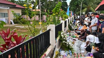 Keluarga korban berkumpul untuk doa bersama dan upacara keagamaan di luar tempat penitipan anak, yang menjadi lokasi penembakan massal di kota Uthai Sawan, Nong Bua Lam Phu, Thailand, Minggu (9/10/2022). [Lillian SUWANRUMPHA / AFP]