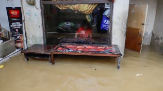 Warga beraktivitas saat banjir yang melanda kawasan Kebon Pala, Jakarta Timur, Senin (10/10/2022). [Suara.com/Alfian Winanto]