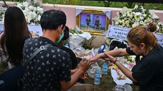 Keluarga korban berkumpul untuk doa bersama dan upacara keagamaan di luar tempat penitipan anak, yang menjadi lokasi penembakan massal di kota Uthai Sawan, Nong Bua Lam Phu, Thailand, Minggu (9/10/2022). [Lillian SUWANRUMPHA / AFP]