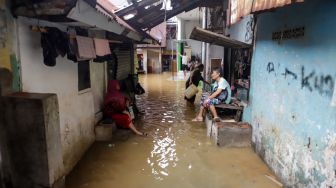 Warga beraktivitas saat banjir yang melanda kawasan Kebon Pala, Jakarta Timur, Senin (10/10/2022). [Suara.com/Alfian Winanto]