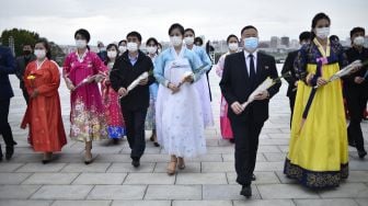 Orang-orang meletakkan bunga untuk memberi penghormatan di depan patung pemimpin Korea Utara Kim Il Sung dan Kim Jong Il di Bukit Mansu, Pyongyang, Korea Utara, Senin (10/10/2022). [KIM Won Jin / AFP]
