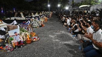 Keluarga dan kerabat berdoa di depan peti mati korban penembakan massal selama upacara kremasi di Na Klang, Provinsi Nong Bua Lam Phu, Thailand, Selasa (11/10/2022). [Lillian SUWANRUMPHA / AFP]