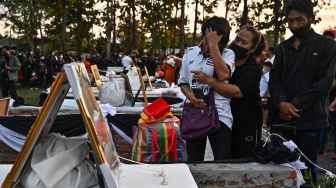 Keluarga dan kerabat berkabung di samping peti mati korban penembakan massal selama upacara kremasi di Na Klang, Provinsi Nong Bua Lam Phu, Thailand, Selasa (11/10/2022). [Lillian SUWANRUMPHA / AFP]