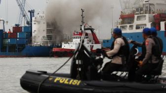 Kapal tunda (tug boat) memadamkan api yang membakar kapal kargo LIT Enterprise di Dermaga Jamrud Selatan, Pelabuhan Tanjung Perak, Surabaya, Jawa Timur, Kamis (13/10/2022). ANTARA FOTO/Didik Suhartono