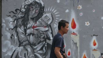 Pejalan kaki melintasi mural bertema tragedi Kanjuruhan di Jalan Simpang Gajayana, Malang, Jawa Timur, Jumat (14/10/2022). [ANTARA FOTO/Ari Bowo Sucipto/rwa].