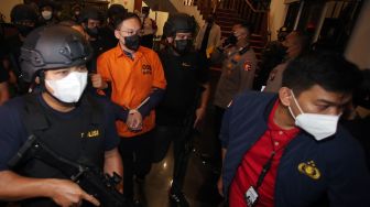 Petugas kepolisian membawa tersangka bandar besar judi online Apin Bak Kim alias Apin BK setibanya dari Malaysia di Bandara Soekarno Hatta, Tangerang, Banten, Jumat (14/10/2022).  ANTARA FOTO/Muhammad Iqbal/