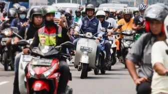 Gubernur DKI Jakarta Anies Baswedan (tengah) menaiki sepeda motor vespa saat melintas di Jalan Jenderal Sudirman, Jakarta Pusat, Minggu (16/10/2022). [Suara.com/Alfian Winanto]