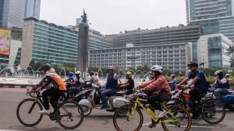 Gubernur DKI Jakarta Anies Baswedan (tengah) menaiki sepeda motor vespa saat melintas di Jalan Jenderal Sudirman, Jakarta Pusat, Minggu (16/10/2022). [Suara.com/Alfian Winanto]