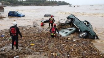 Petugas penyelamat mencoba mengevakuasi kendaraan yang terbawa banjir bandang di Pantai Agia Pelagia, Pulau Kreta, Yunani, Sabtu (15/10/2022). [AFP] 
