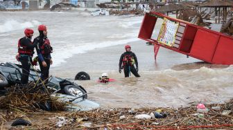 Petugas penyelamat melakukan pencarian korban yang terbawa banjir bandang di sepanjang Pantai Agia Pelagia, Pulau Kreta, Yunani, Sabtu (15/10/2022). [AFP]