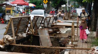 Pejalan kaki melintas disamping proyek galian saluran di Pejaten, Pasar Minggu, Jakarta Selatan, Selasa (18/10/2022). [Suara.com/Alfian Winanto]