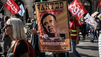 Seorang pria memegang 'poster buronan' yang menggambarkan kepala Total Energie selama demonstrasi di kota barat Bordeaux, Prancis, Selasa (18/10/2022). [Thibaud MORITZ / AFP]
